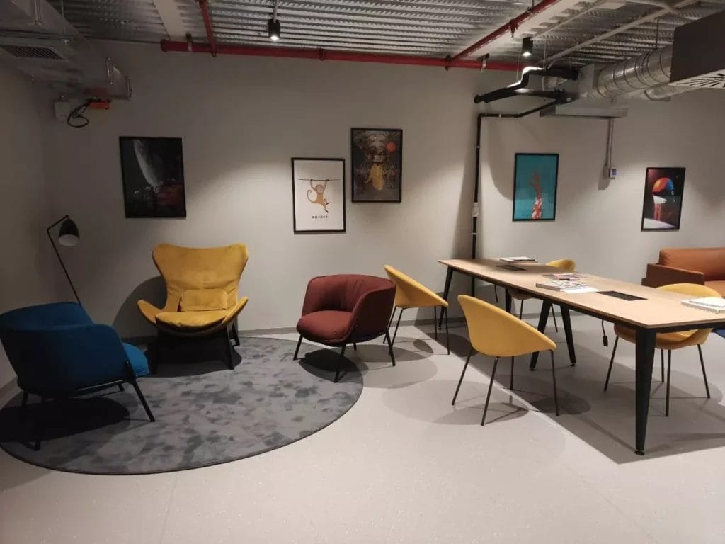 Area living del the social hub florence belfiore con poltrone colorate e tavolo riunioni.